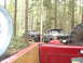 1989 Ford Bronco - Two off-road vehicles are parked on a trail surrounded by tall trees in a wooded area.