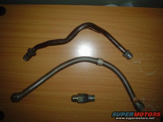 Two metal fuel lines and a connector fitting on a wooden surface