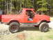 1989 Ford Bronco - This modified red SUV sits in a forest clearing, ready for adventure.
