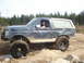 1989 Ford Bronco - A modified Ford Bronco navigates a rocky, muddy off-road course with a driver inside.