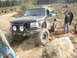 1989 Ford Bronco - Modified 1989 Ford Bronco navigating a rocky, off-road trail with friends watching.