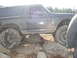 1989 Ford Bronco - A heavily modified Ford Bronco is shown traversing a rocky terrain, with its suspension clearly visible.