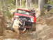 1989 Ford Bronco - A red 1989 Ford Bronco is being winched through a challenging rocky trail with assistance from people and another vehicle.