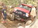 1989 Ford Bronco - A red off-road vehicle is being winched through a challenging rocky obstacle course with onlookers present.