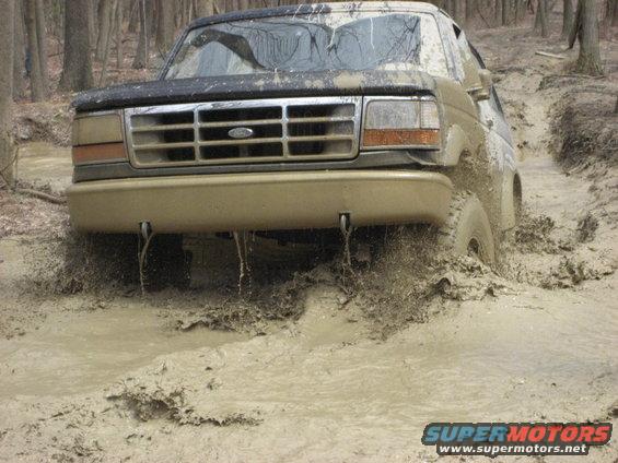 Muddy 1992 Ford Bronco front end deep in mud, splashing water