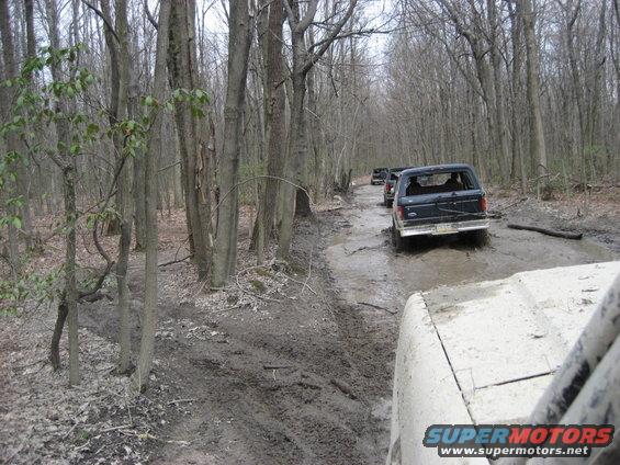 1991 Ford Bronco driving rear view on muddy forest road