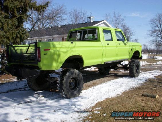 Lime green lifted crew cab pickup truck with large tires, seen from the rear