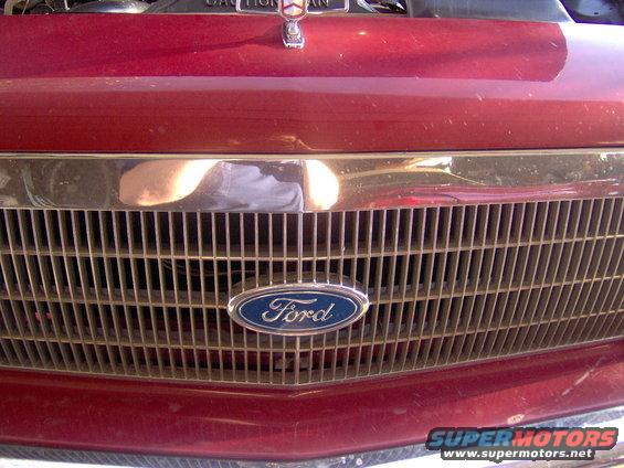 Red vehicle grille with a chrome trim and vertical bars, a blue Ford oval emblem