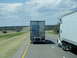 2009 Kenworth T800 - Two semi-trucks travel down a highway under a cloudy sky.