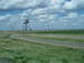 2009 Kenworth T800 - A water tower and a striped tower are visible in a rural landscape with a road curving through it.
