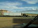 2009 Kenworth T800 - A semi-truck and trailer travels down the highway past a hotel under a cloudy sky.