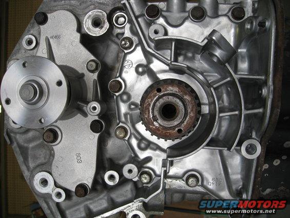 Close-up of an engine block with a water pump pulley and timing gear visible