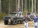 1979 Ford Bronco - Several off-road vehicles are parked on a dirt path surrounded by tall trees.