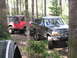 1979 Ford Bronco - Two off-road vehicles navigate a wooded trail, with a black Ford Bronco leading the way.