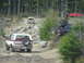 1979 Ford Bronco - Several off-road vehicles navigate a challenging, rocky path through a dense forest.