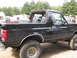 1979 Ford Bronco - Side view of a black SUV with a removable roof and off-road tires.
