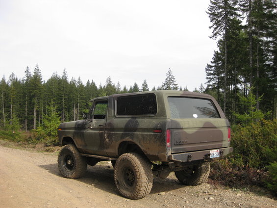 Camouflage 1979 Ford Bronco rear 3/4 view on dirt road