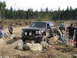 1979 Ford Bronco - Black Ford Bronco is being helped over rocks by people while another SUV follows behind.