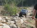 1979 Ford Bronco - An off-road SUV navigates a challenging rocky trail in a wooded area.