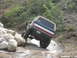 1979 Ford Bronco - This Ford Bronco is navigating a challenging off-road course with large rocks and mud.