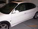 1995 Ford Taurus - Side view of a white sedan, parked indoors with another vehicle in the background.