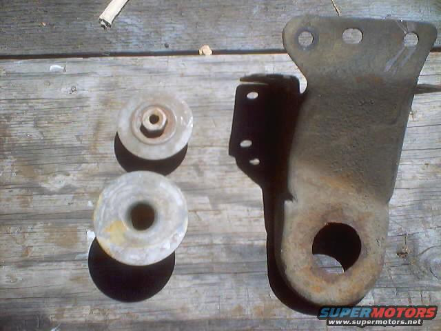 Two round rubber bushings and a rusty metal bracket with a large hole