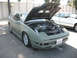 1995 Ford Probe - A matte green coupe with its hood open, revealing the engine bay, parked next to a white car.