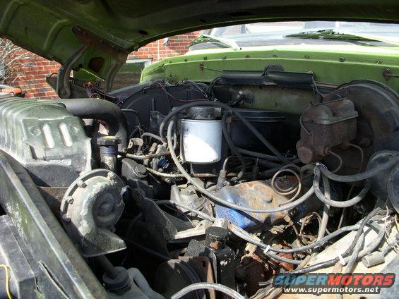 Green 1974 Ford F-350 engine bay with visible V8 engine, radiator, and brake fluid reservoir