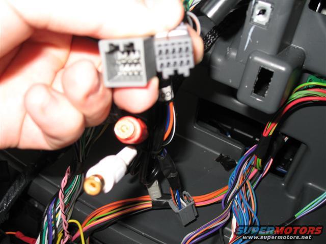 hand holding a gray electrical connector with wires visible