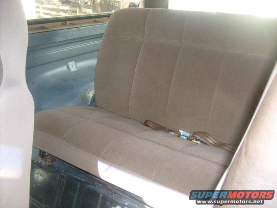 Rear bench seat with brown fabric upholstery and a seatbelt