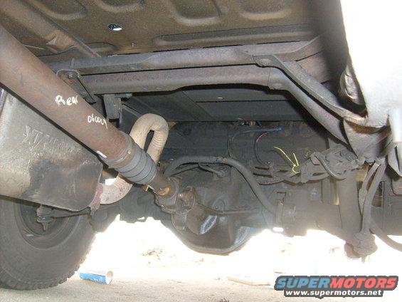 Undercarriage view showing driveshaft, differential, and exhaust pipe. Handwritten text 'Rear' and '01004' on driveshaft