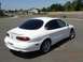1995 Ford Taurus - This white sedan, likely a 1996 model, is shown from the rear-left quarter on a paved road with houses in the background.