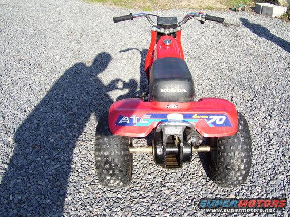 Red Honda ATC 70 three-wheeler parked on gravel. Has 'ATC' and '70' decals