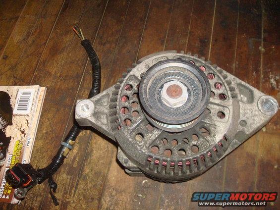 Automotive alternator with pulley and wiring harness on wooden surface