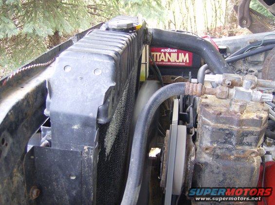 Radiator and engine parts, including a red Autocraft Titanium battery, in a vehicle's engine bay