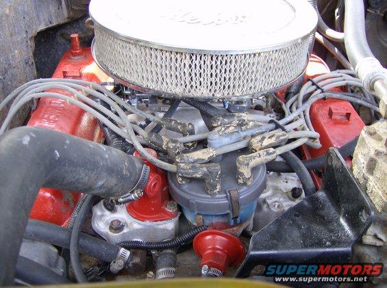 Engine bay showing air filter, distributor cap, spark plug wires, and red valve covers