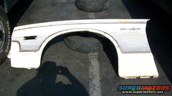 White Ford fender with "Aero Squire" script, lying on asphalt
