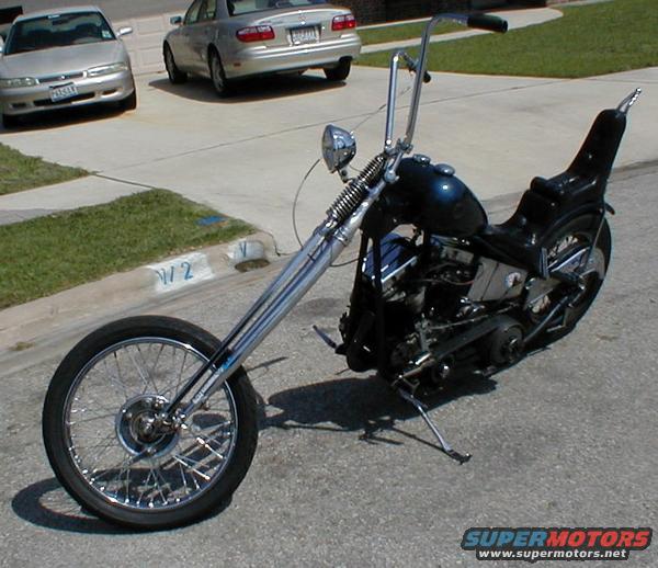 Dark blue chopper motorcycle with extended front forks, ape hanger handlebars, and a stepped seat
