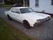 1966 Oldsmobile Cutlass - A white 1966 Oldsmobile 98 sedan sits parked on a gravel driveway next to a white house.