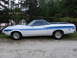 1972 Ford Ranchero - A white 1972 Ford Ranchero with blue racing stripes is seen from the side parked near a body of water.