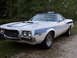 1972 Ford Ranchero - A white and blue 1972 Ford Ranchero with distinctive hood scoops and side stripe is parked outdoors.