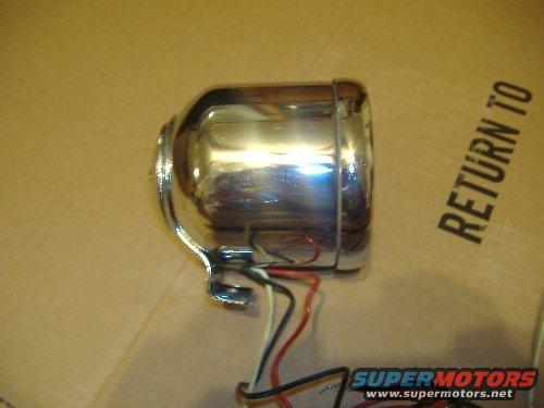 Chrome headlight assembly with red, black, and white wires. Cardboard box with 'RETURN TO' text visible