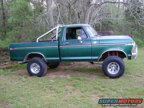 1979 Ford F-150 pickup truck, green, lifted, with roll bar in bed, parked on grass