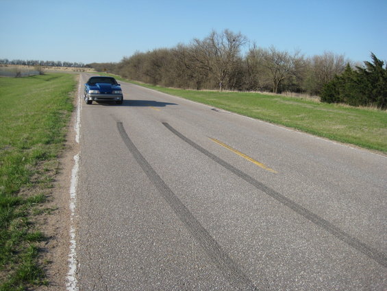 Blue 1990 Ford Mustang convertible with tire marks on a rural road