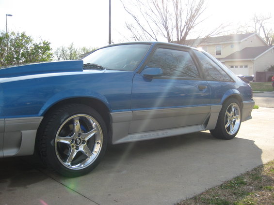 Blue coupe with a cowl induction hood and silver lower trim. The side reads 'Mustang GT'