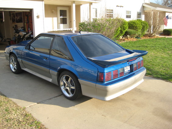 Blue 1990 Ford Mustang coupe with a rear spoiler and tinted windows
