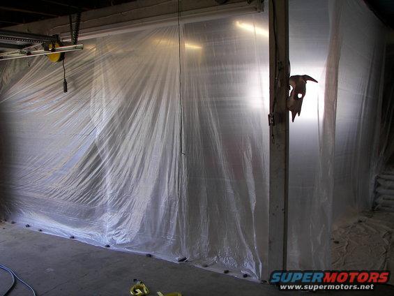 Plastic sheeting covers a garage area, obscuring any vehicles within