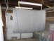 1987 Ford Bronco - Car hood prepared for painting, hanging in a garage with fluorescent lights overhead.