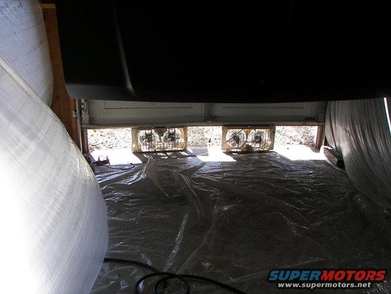 Garage interior with plastic sheeting on floor and two fans in doorway