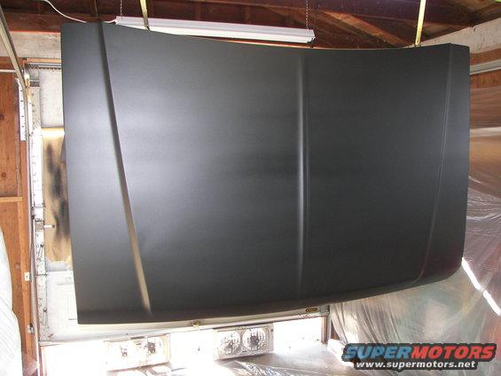 Dark gray hood hanging in a garage, possibly being painted